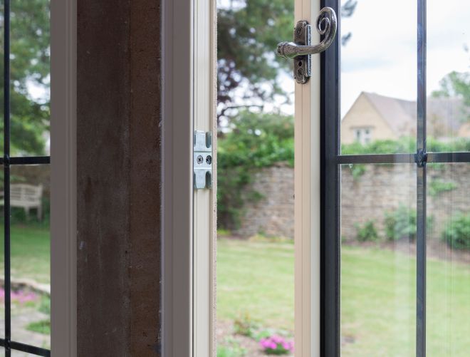 A slightly open window leading to a large garden