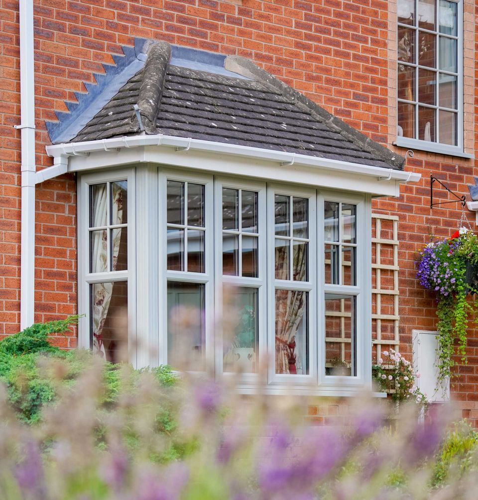 windows on the front of a house with flowers out of focus