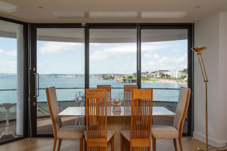 sliding patio doors behind a kitchen table with the ocean in view