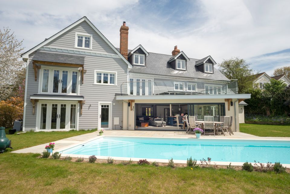 wide shot of large home with balcony, swimming pool and all windows in view