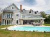 wide shot of large home with balcony, swimming pool and all windows in view